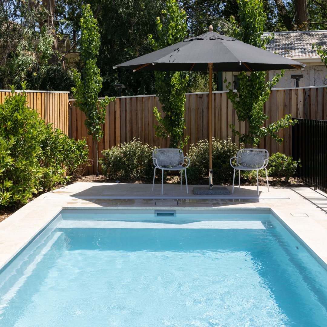 Rectangular pool with a timber fence and an outdoor umbrella in a Canberra backyard