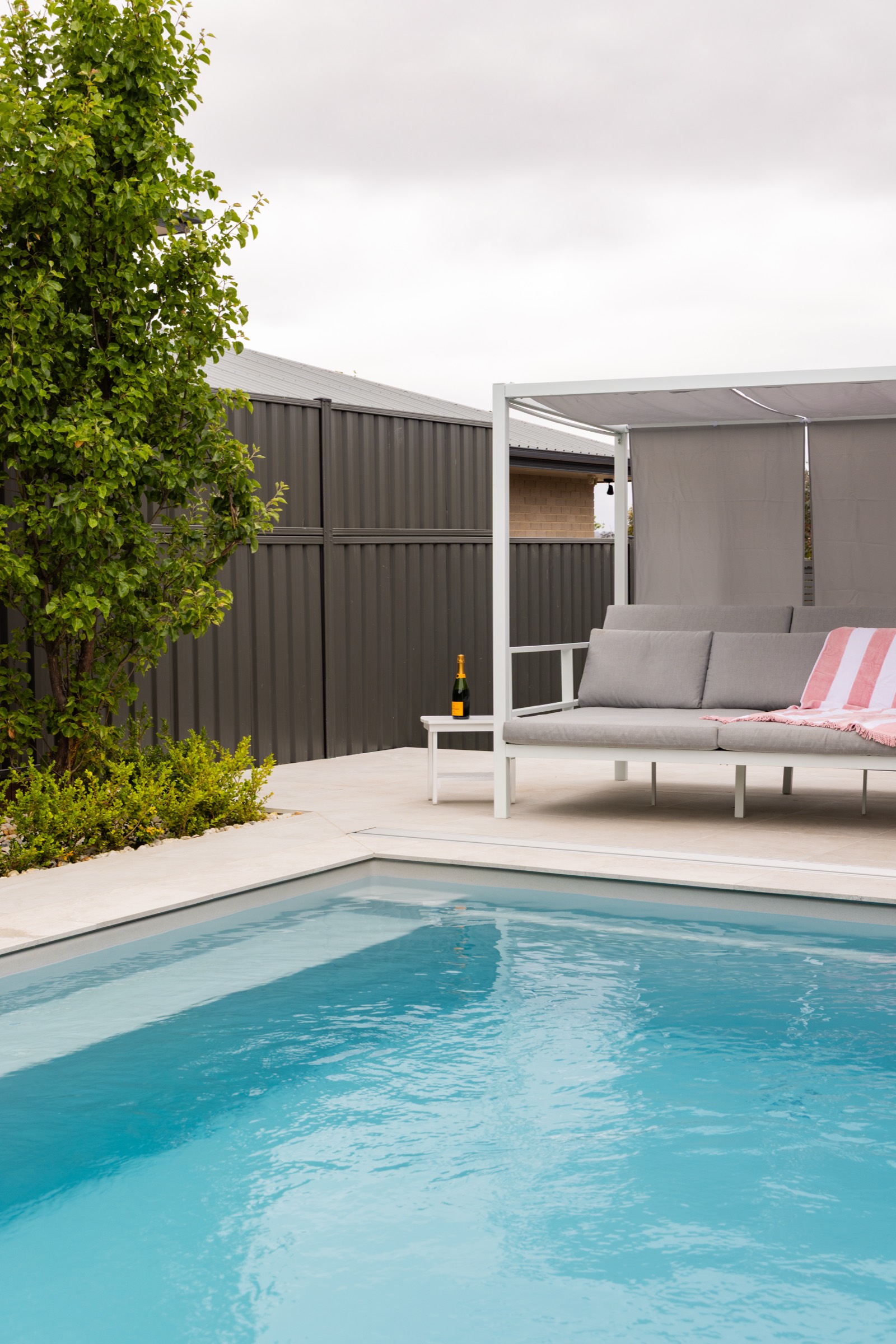 Clean pool water beside a shaded outdoor daybed